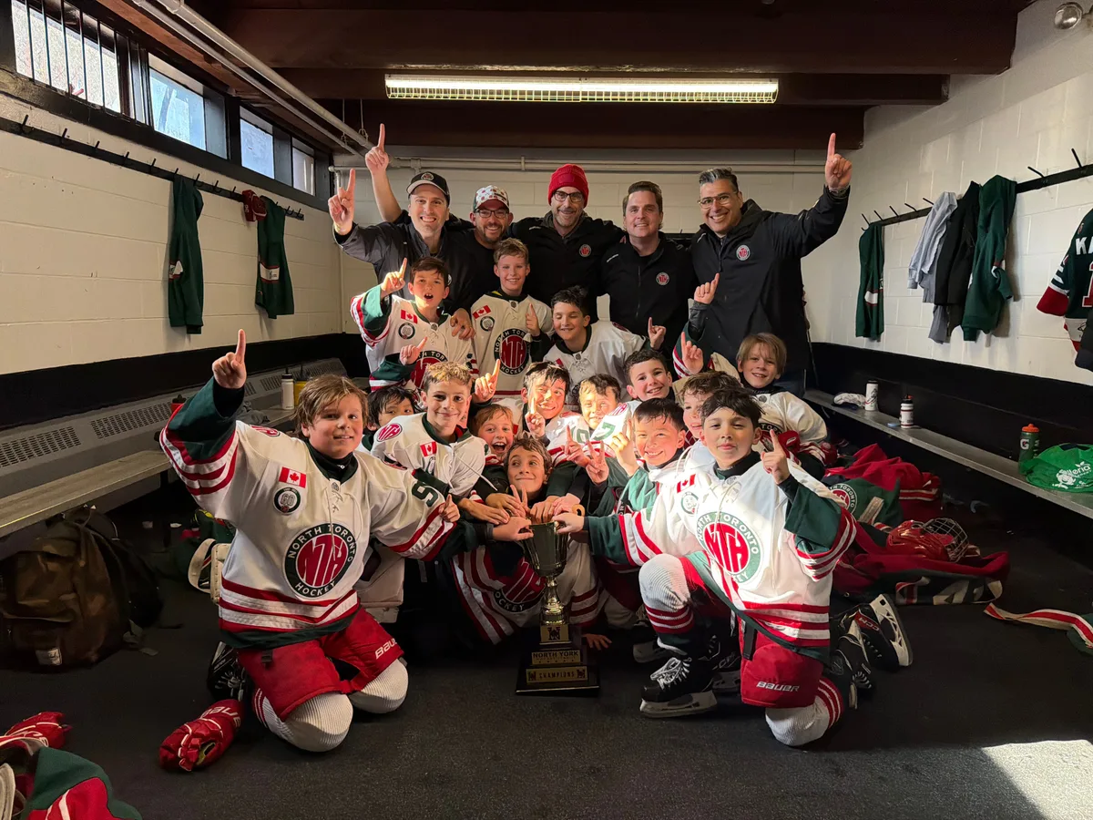 North Toronto U10 Select team celebrating their NYHL U10 Tier 1 League championship in the locker room, holding the trophy